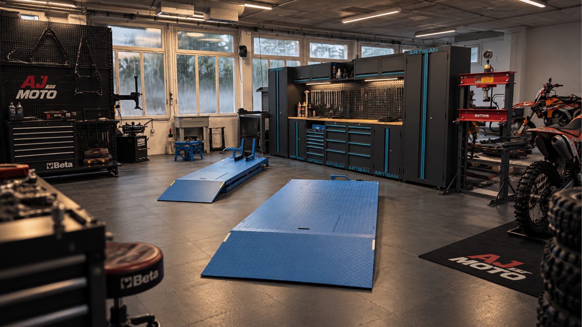 Zone technique de l’atelier AJ Moto : ponts élévateurs moto, presse hydraulique, servantes Beta et établi d’outillage