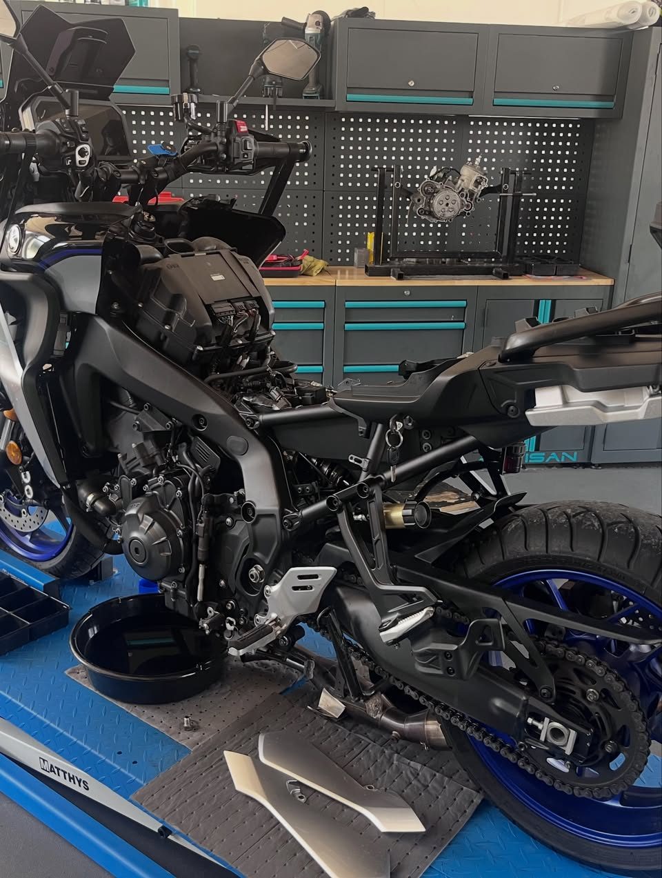 Trail Yamaha carénages déposés sur le pont de l’atelier AJ Moto, bac de vidange en place